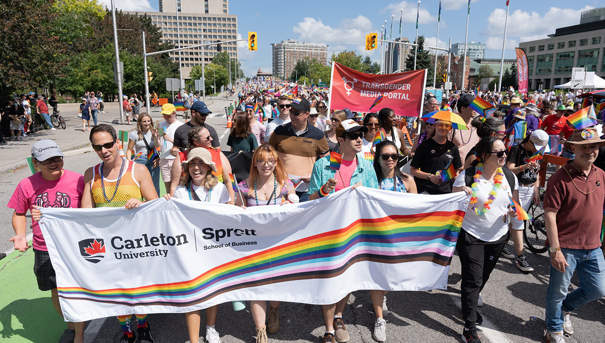 A large crowd marching during a festival holding a banner