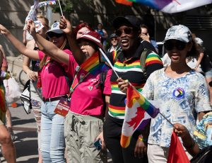 A small group of people waving Pride flags during a parade
