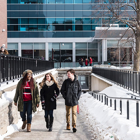 Three students walking together up a ramp during winter