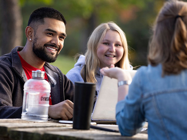 Carleton University students sitting on a picnic table and chatting
