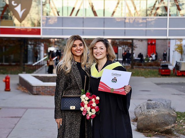 Two people posing for a picture, one holding a degree