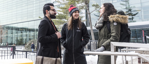 Students stand outside on a winter day and talk to each other.