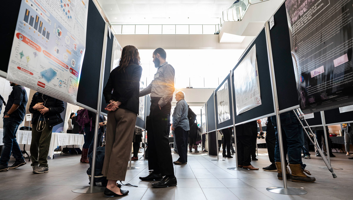 A Data Day 6.0 participant shows her poster competition entry to a judge.