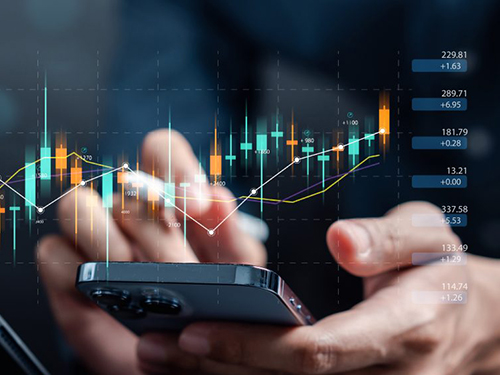 A pair of hands holding a mobile phone. Financial charts appear to be coming out of the mobile phone screen.