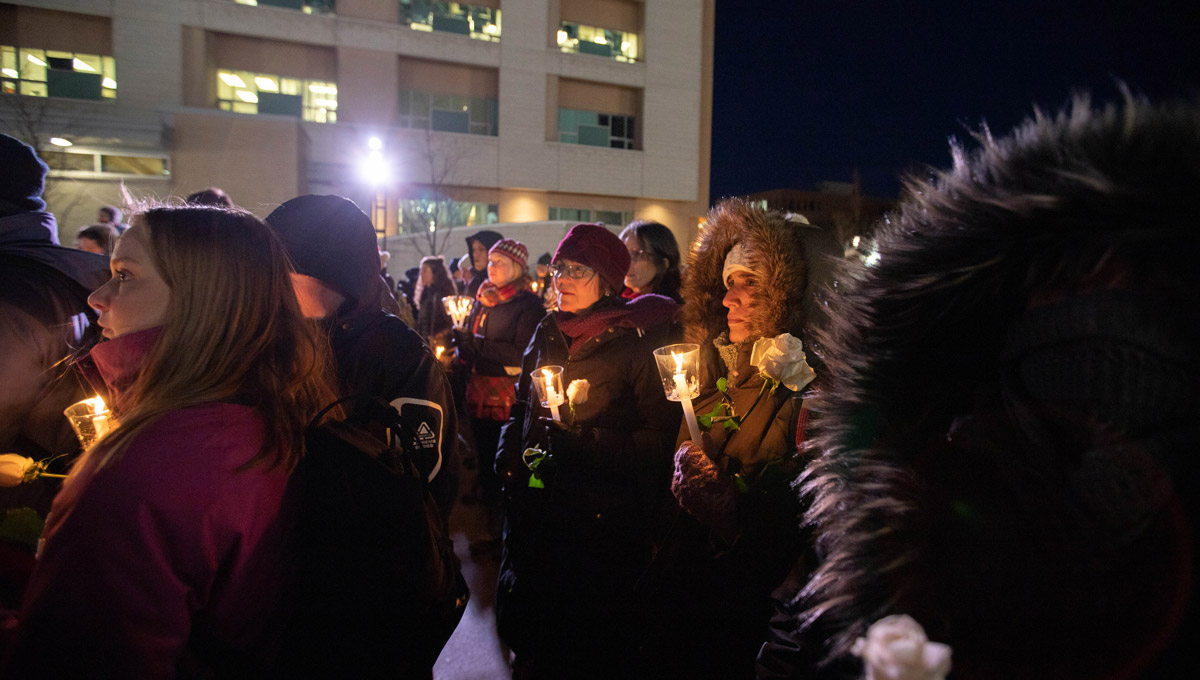 Women with candles stand in memoriam at uOttawa during a vigil commemorating victims of the Montreal Massacre.
