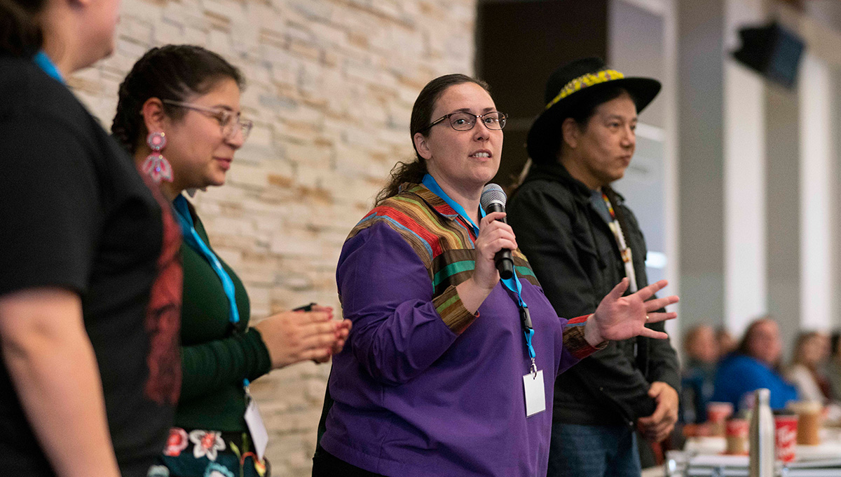 The image features Benny Michaud speaking to attendees at the Annual Round Dance.