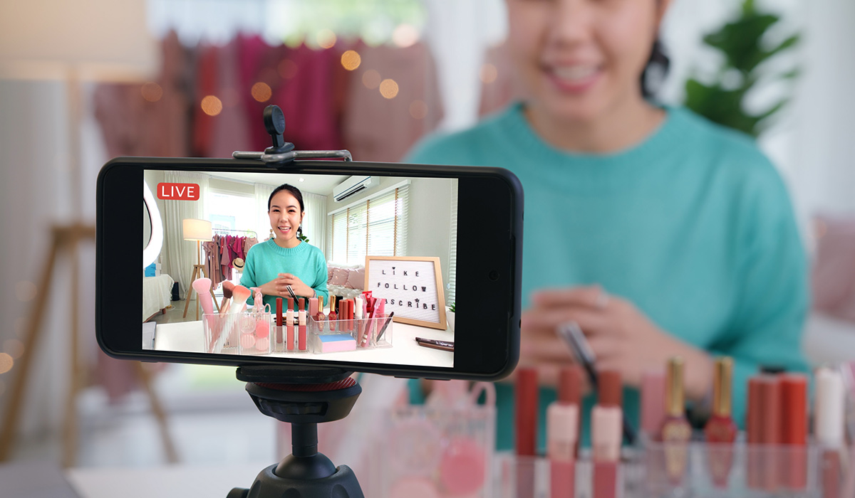 A close up of a mobile phone recording a video of a young woman talking about makeup.