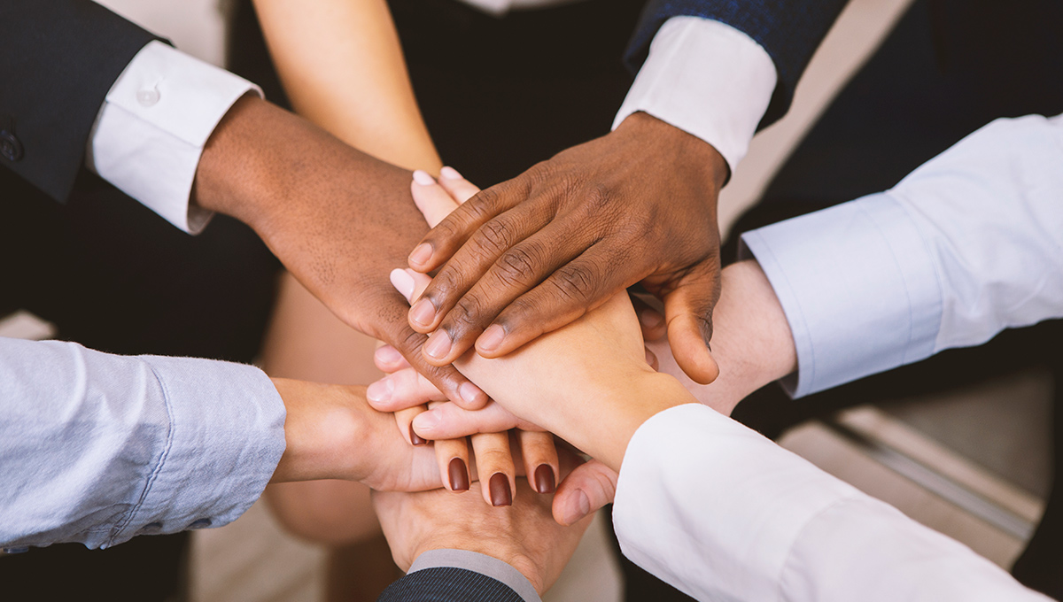 Multiethnic corporate teame stacking hands together in office