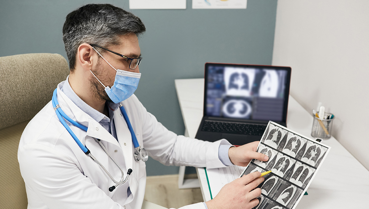 Doctor wearing a protective face mask analyzes results of a patient's lungs CT scan at a medical clinic