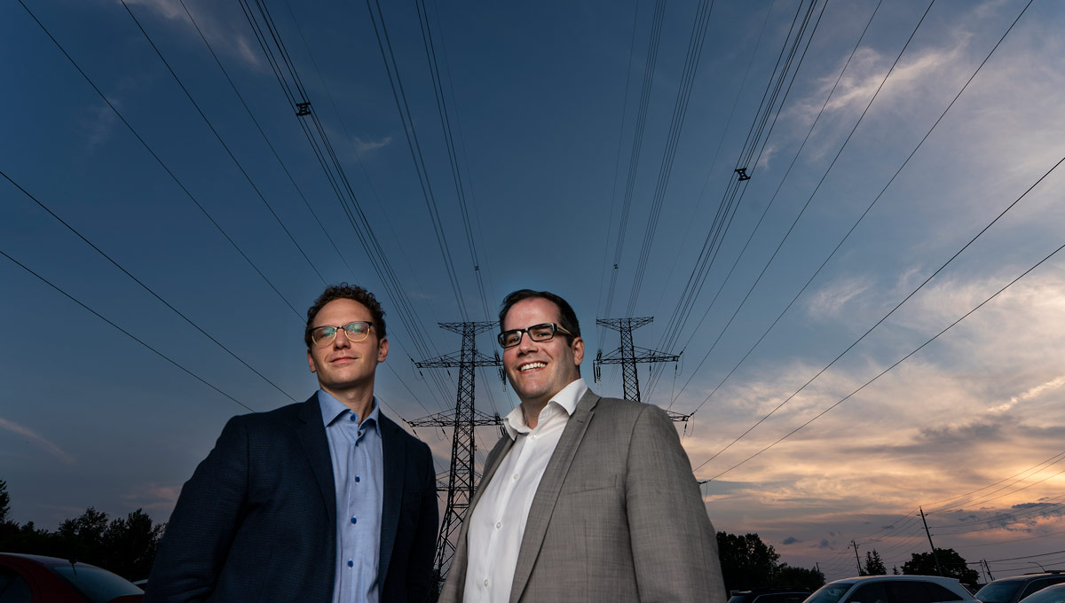 Casey Babb and Alex Wilner stand in front of power lines at a clear evening. Prof. Alex Wilner and PhD candidate Casey Babb have been awarded a research grant for their project assessing threats to Canada's energy sector.