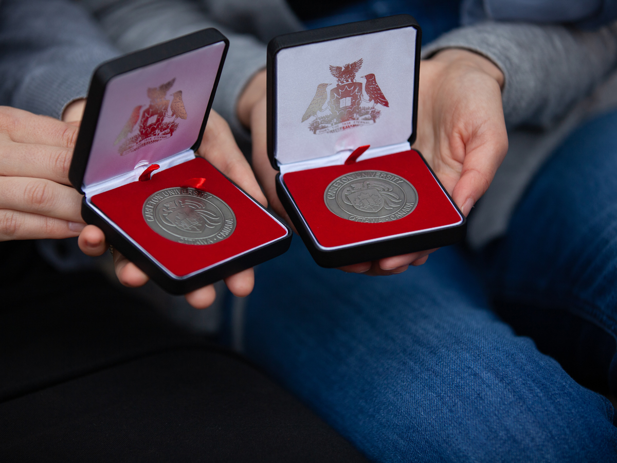 A closeup of two hands holding medals.