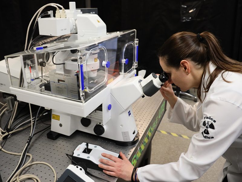 A scientist peers into the lens of a high-powered microscope.