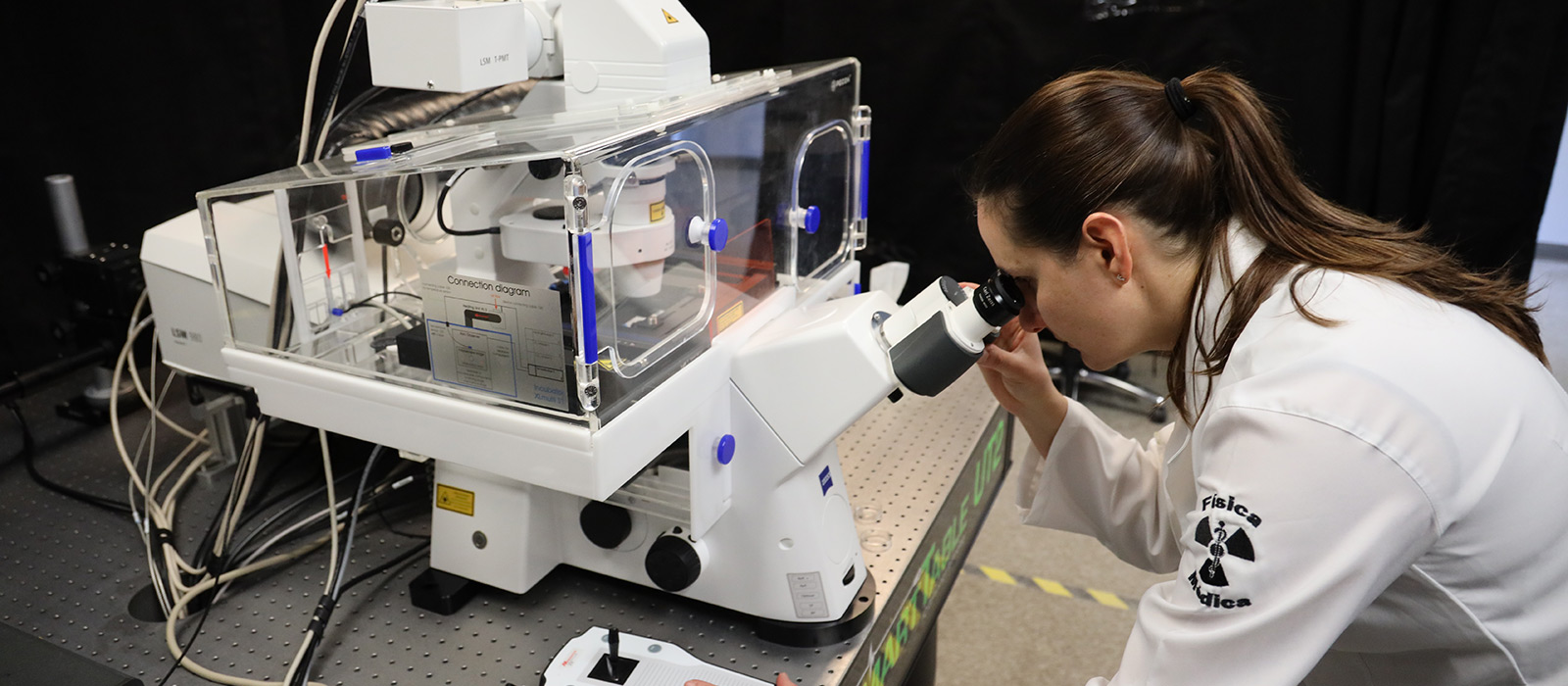 A scientist peers into the lens of a high-powered microscope