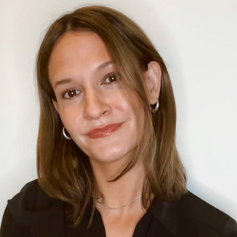 A headshot of a woman with brown hair and a black shirt.