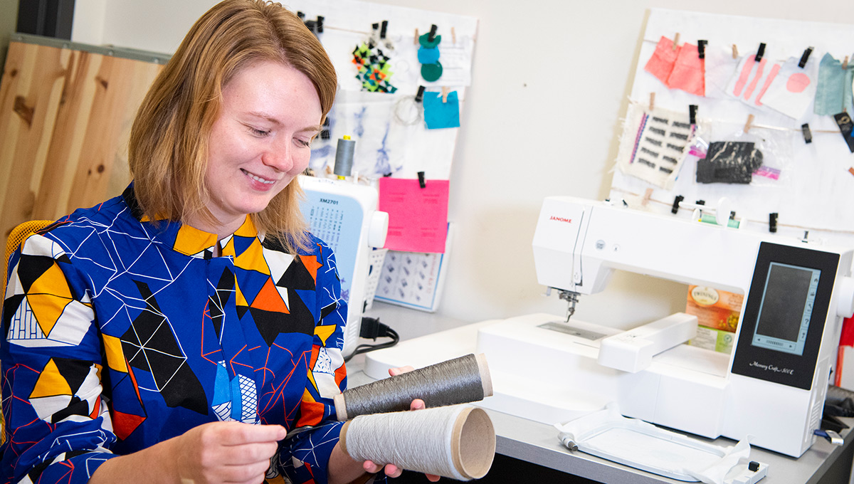 PhD student Lee Jones holding rolls of yarn.