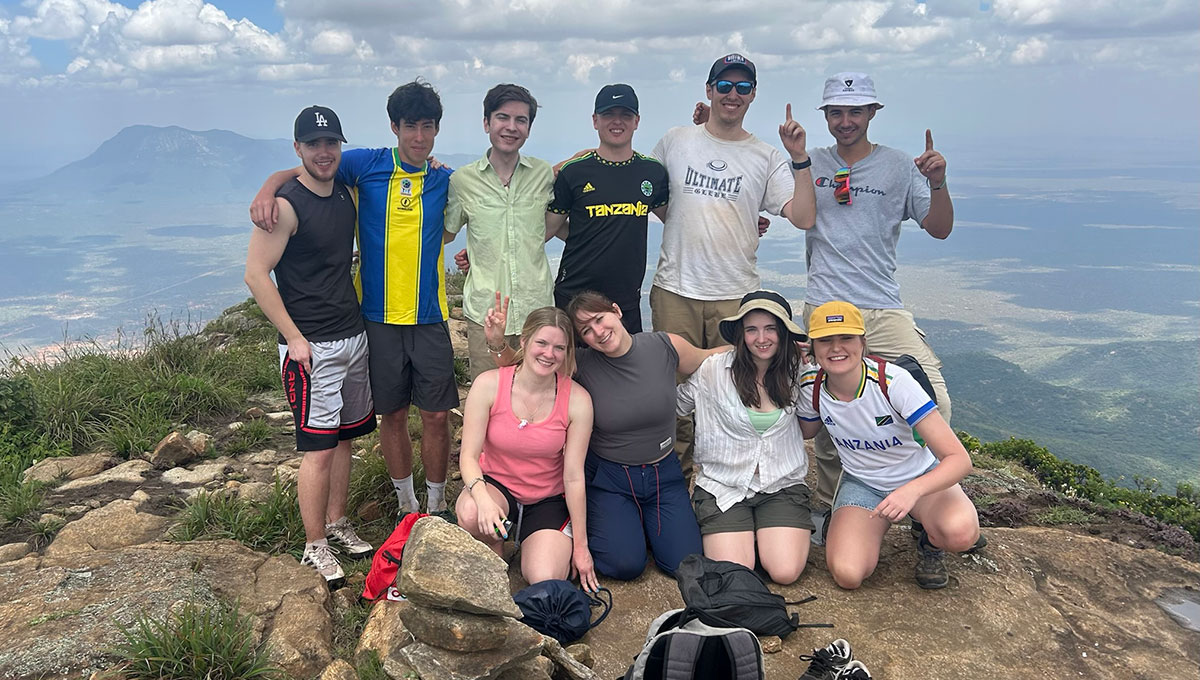 A large group of people posing for a photo on a mountain top.