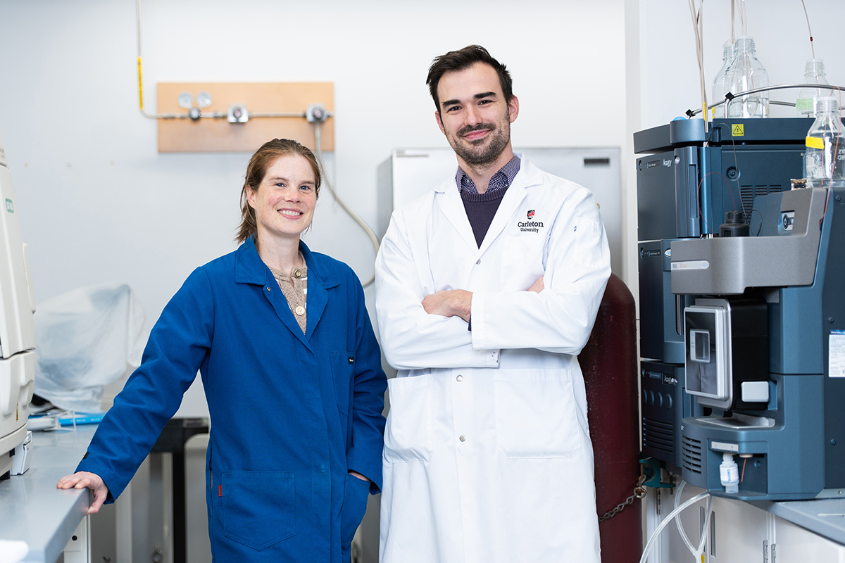 A man and a woman wearing lab coats stand together for a photo inside a labratory.