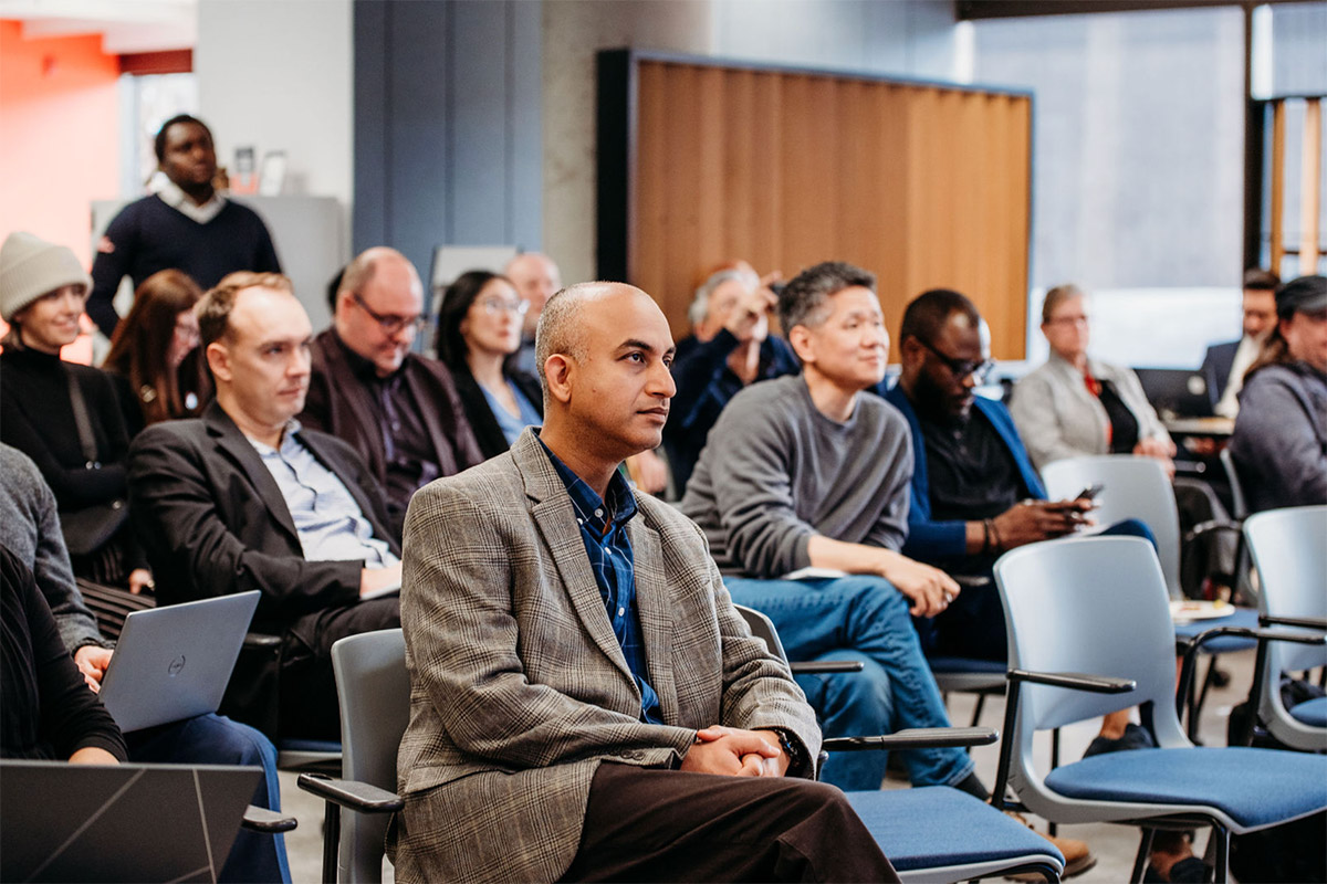 A large group of people sitting in chairs as the audience of an event.