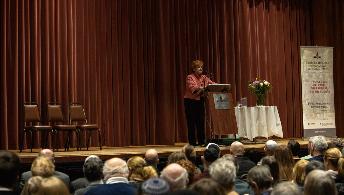 Historian Deborah Lipstadt speaks at a podium while the audience listens.