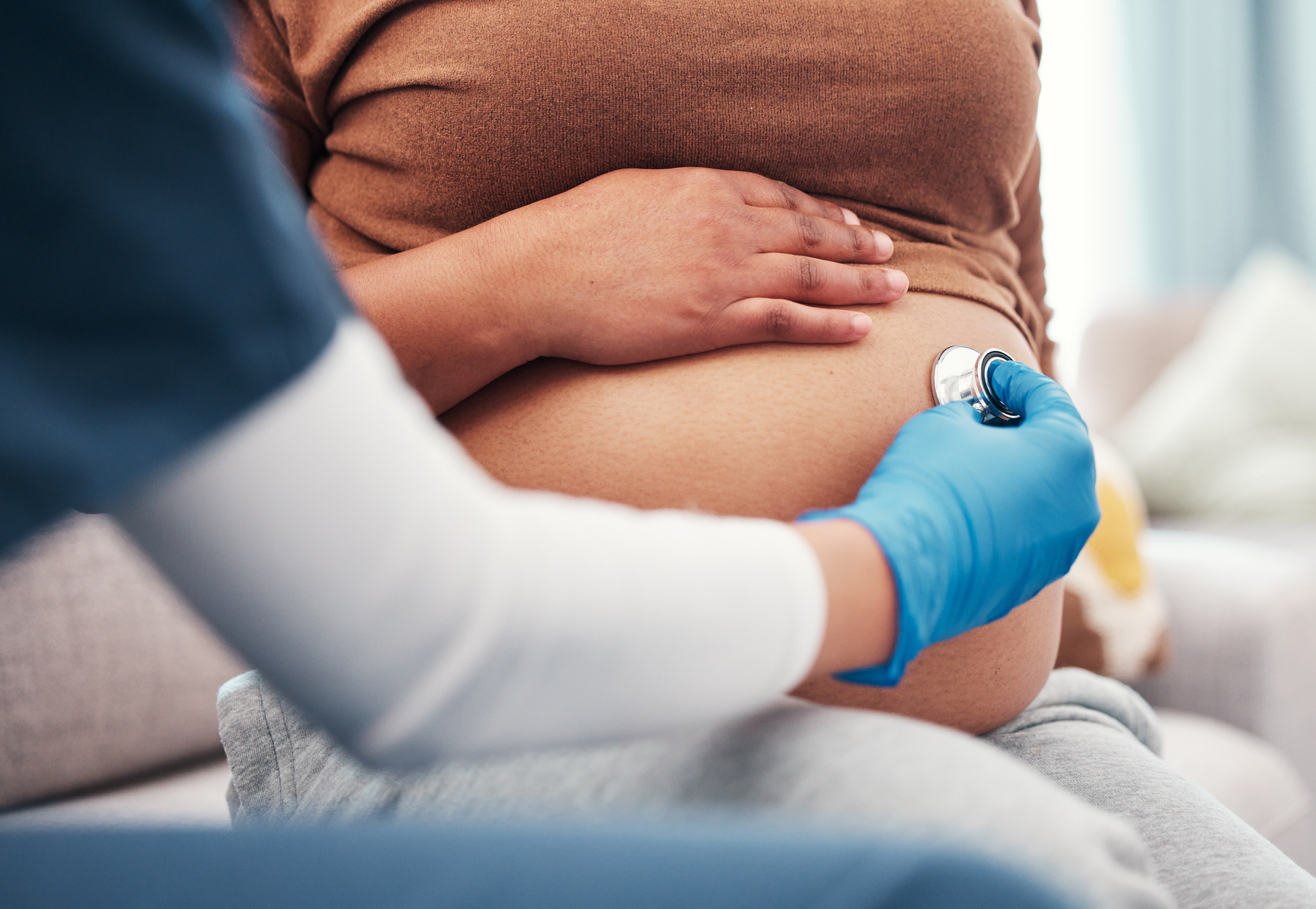 Closeup, pregnant and woman with healthcare checkup and stomach with wellness, appointment and results. Zoom, pregnancy and female with doctor, stethoscope and medical professional for consultation