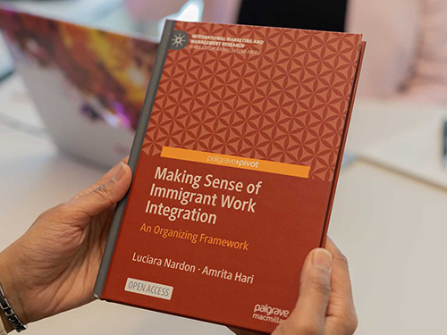 A pair of hands holding a book with the title Making Sense of Immigrant Work Integration
