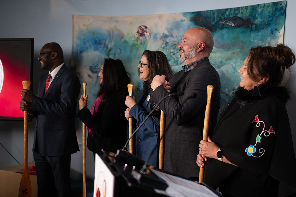 A group of people holding oars at an event celebrating Indigenous journalists.