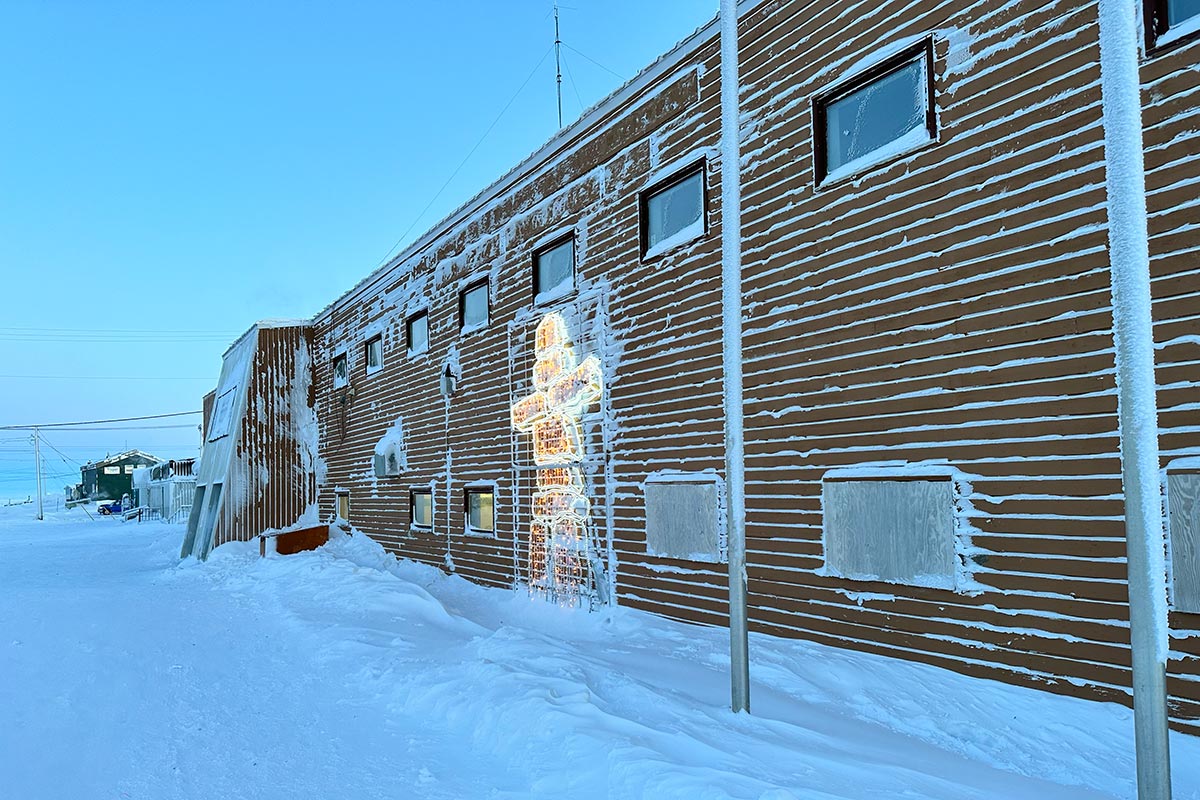 The side of a brick building with snow covering the ground.