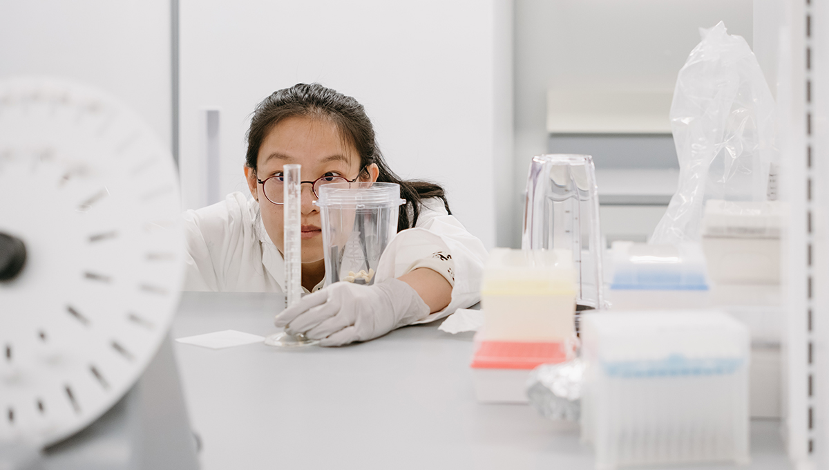 A scientist crouches down to examine a component of an experiment