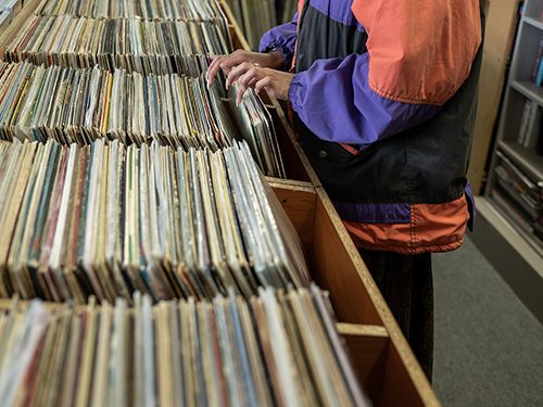 A person digging through vinyl record crates at a music store.