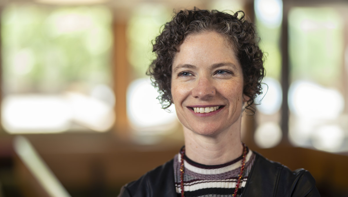 A headshot of Prof. Jacqueline Kennelly indoors as sun shines in through windows.