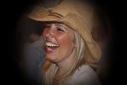 A woman wearing a cowboy hat laughing.