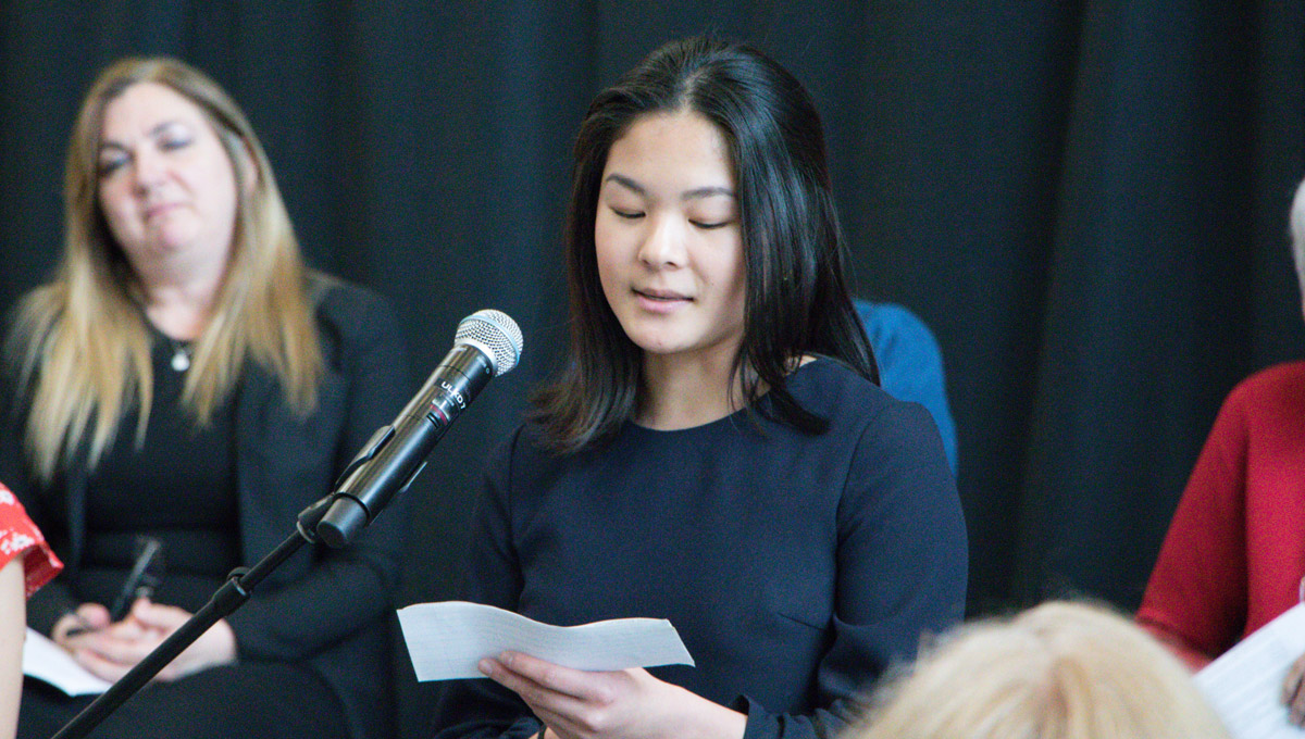 A girl reads from a card as she speaks into a microphone during the International Year of the Child celebration.