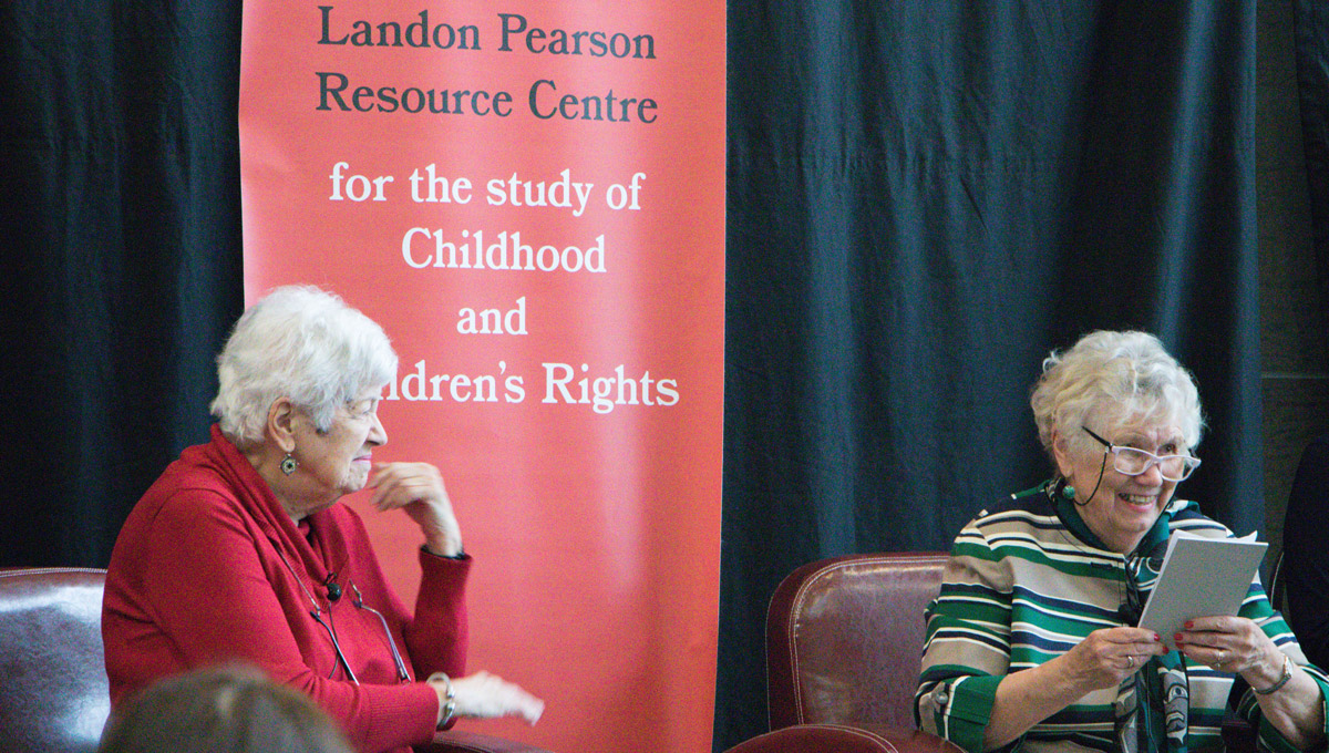 Landon Pearson speaks in front of a large pull--up banner.