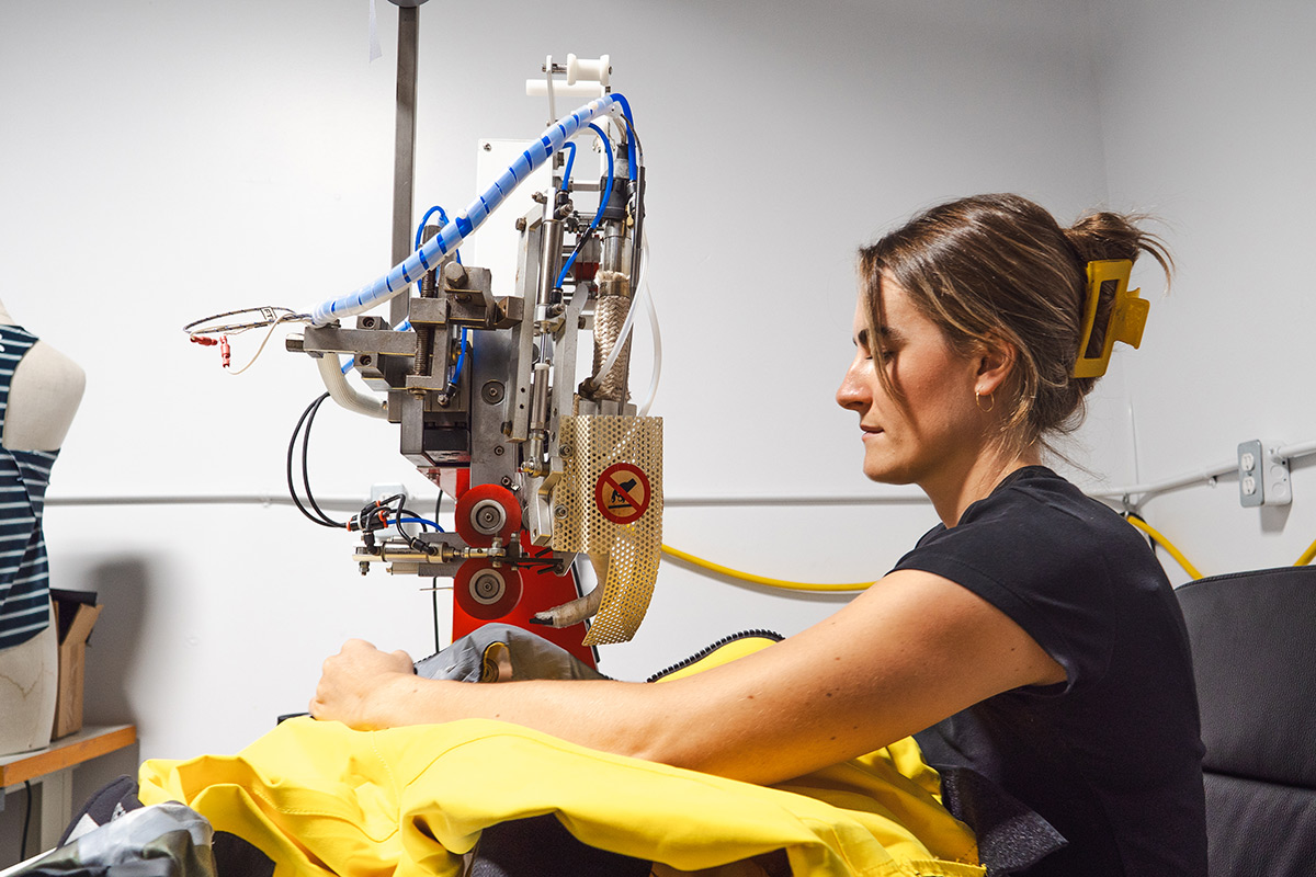 A woman works on an industrial design machine to create outdoor gear.