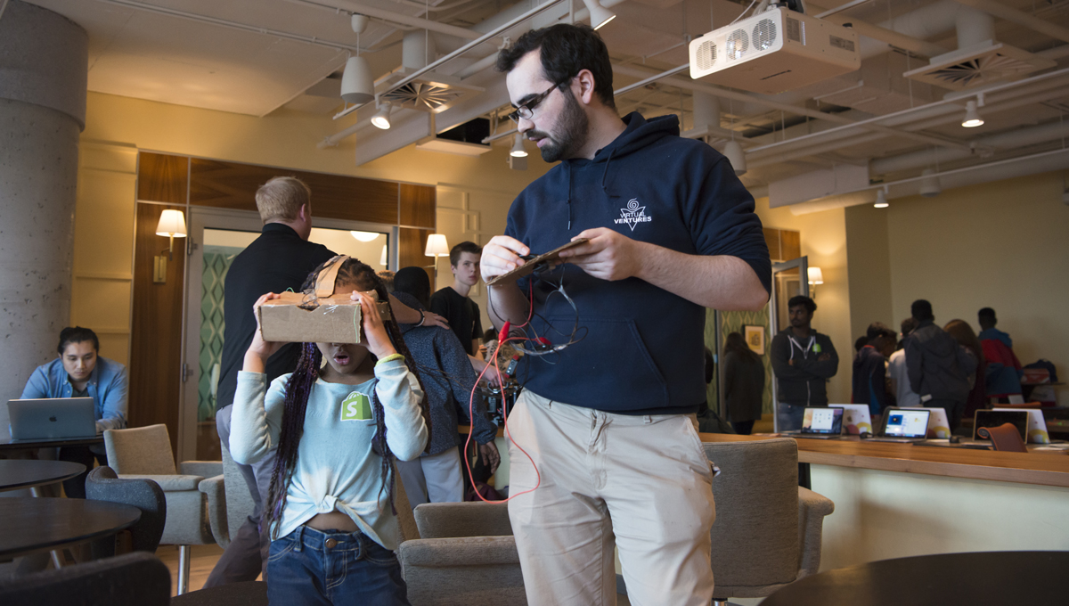 A collaboration between Carleton’s Virtual Ventures, Shopify and the Boys and Girls Club of Ottawa. aims to create digital literacy programs for youth. Pictured: a girl learns about VR by experiencing Google Cardboard under the supervision of a Virtual Ventures staffer.