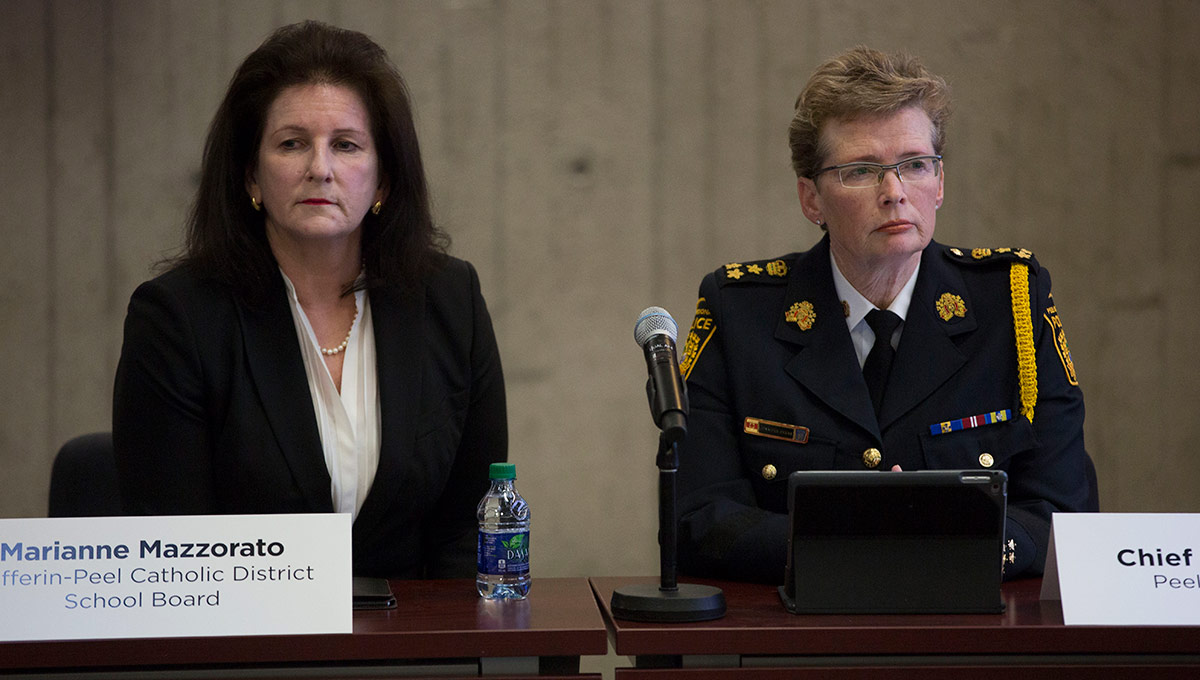 An academic director and police chief sit on a panel with microphones to discuss the subject of police in schools