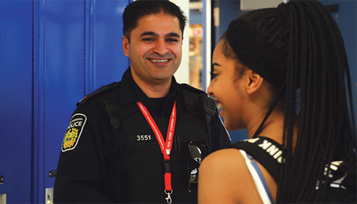 A uniformed officer and teenager are smiling