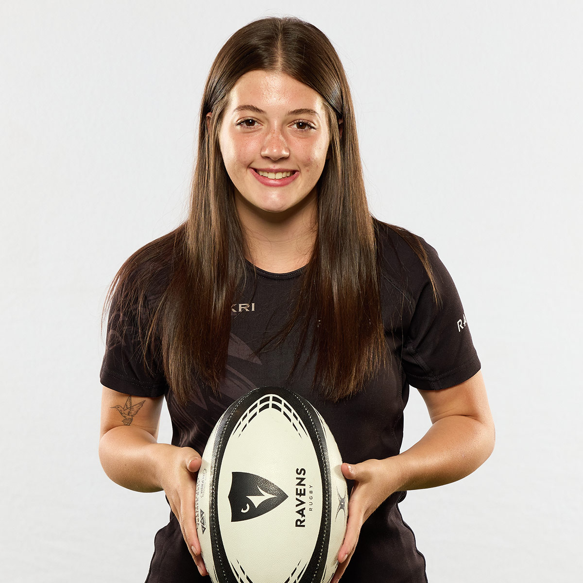 A rugby player holds a rugby ball while posing for a picture.