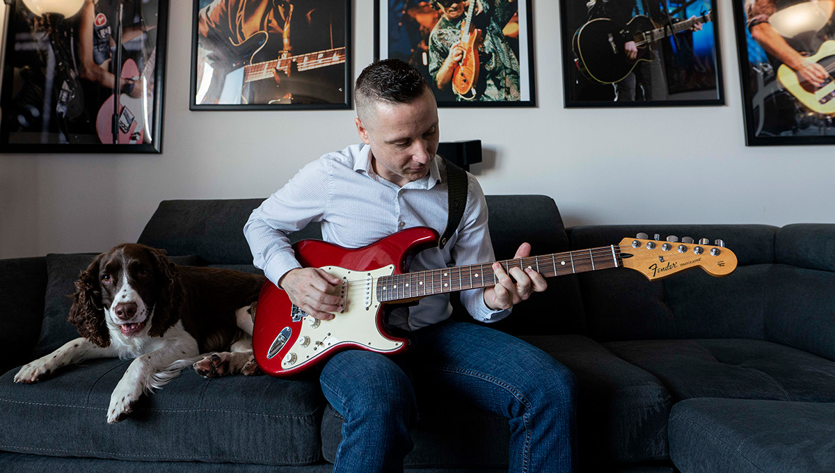 Mickey Magennis plays guitar next to his dog