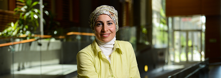 A headshot of Nadia Abu-Zahra, who will focus on Building Communities, in a spacious hallway.