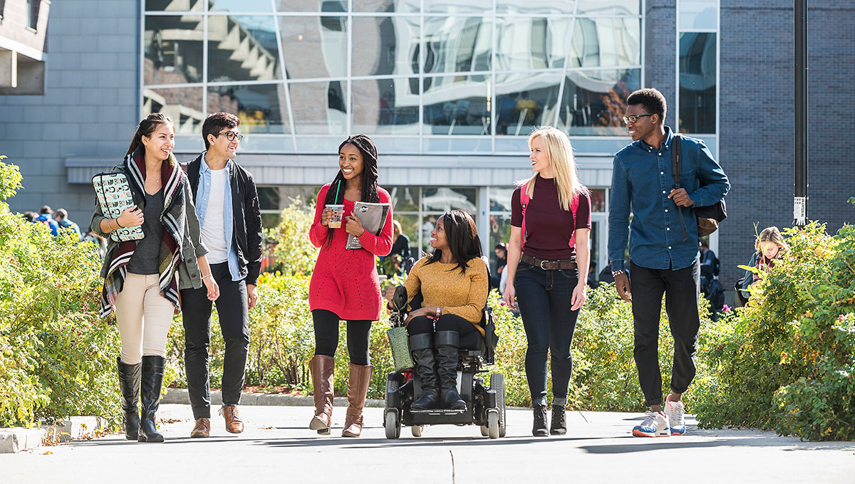 Group of Carleton University walking on campus; the student in the middle is using a wheelchair.