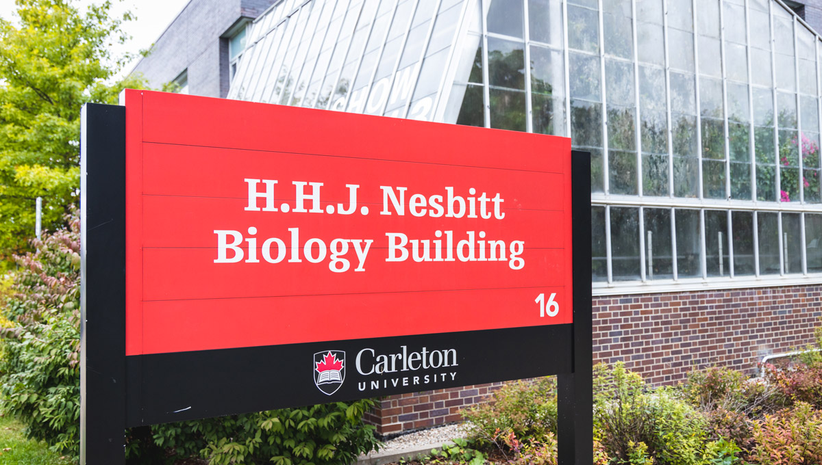 An close up of an exterior sign at the Nesbitt Biology Building on a cloudy fall day.