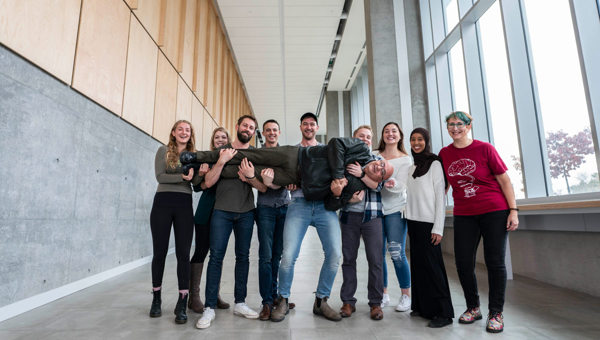 Students and in Carleton's Neuroscience program hold Prof. Alfonso Abizaid in the entrance hallway of the new Health Sciences Building. The Society for Neuroscience Ottawa Chapter, comprised mostly of Carleton University volunteers, has won the Society for Neuroscience’s 2018 Chapter of the Year (COY) Award—a prestigious recognition of its unique outreach in teaching people about the brain.