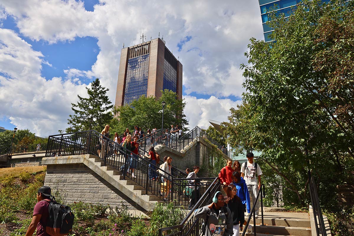 A large group of people ascending and descending an outdoor staircase, with a large office building visible in the background.