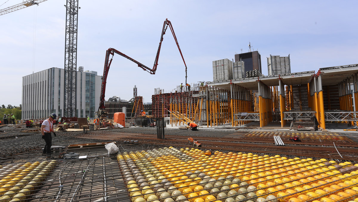 A machine adds concrete to the structure, with the void concrete slab system in the foreground, manufactured by BubbleDeck North America LLC.