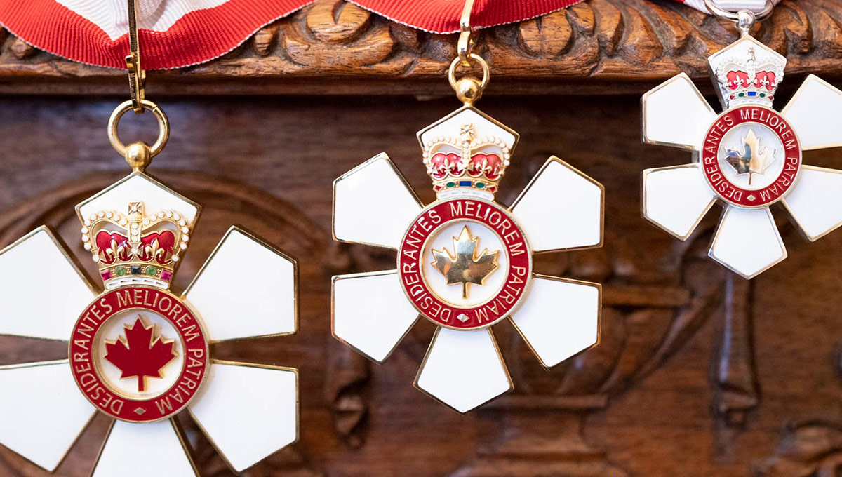 3 Order of Canada insignias hanging from a ribbon.