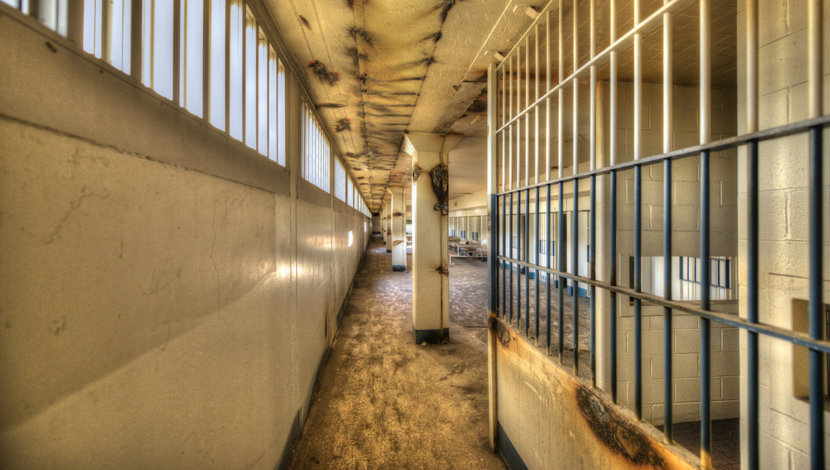 The hallway of a prison, with bars from a prison cell visible