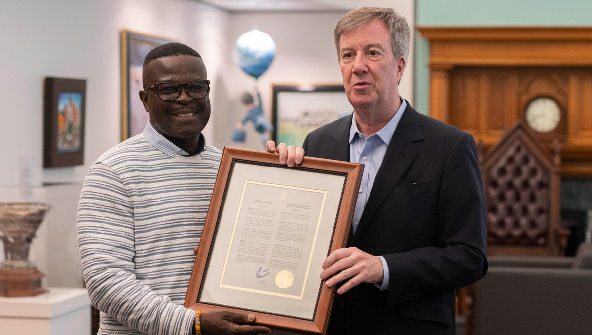 Mayor Jim Watson and a visiting Queen Elizabeth Scholarship- Advanced Scholars hold a framed proclamtion City Hall.