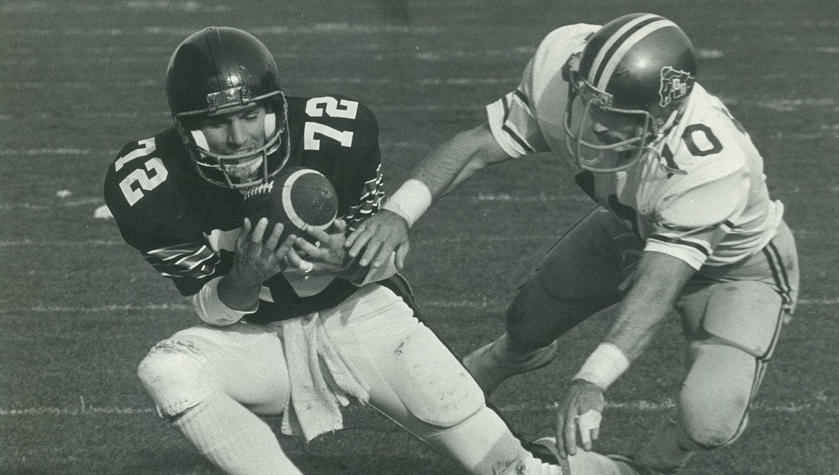 A black and white photo of a Carleton Raven catching a ball during a game.