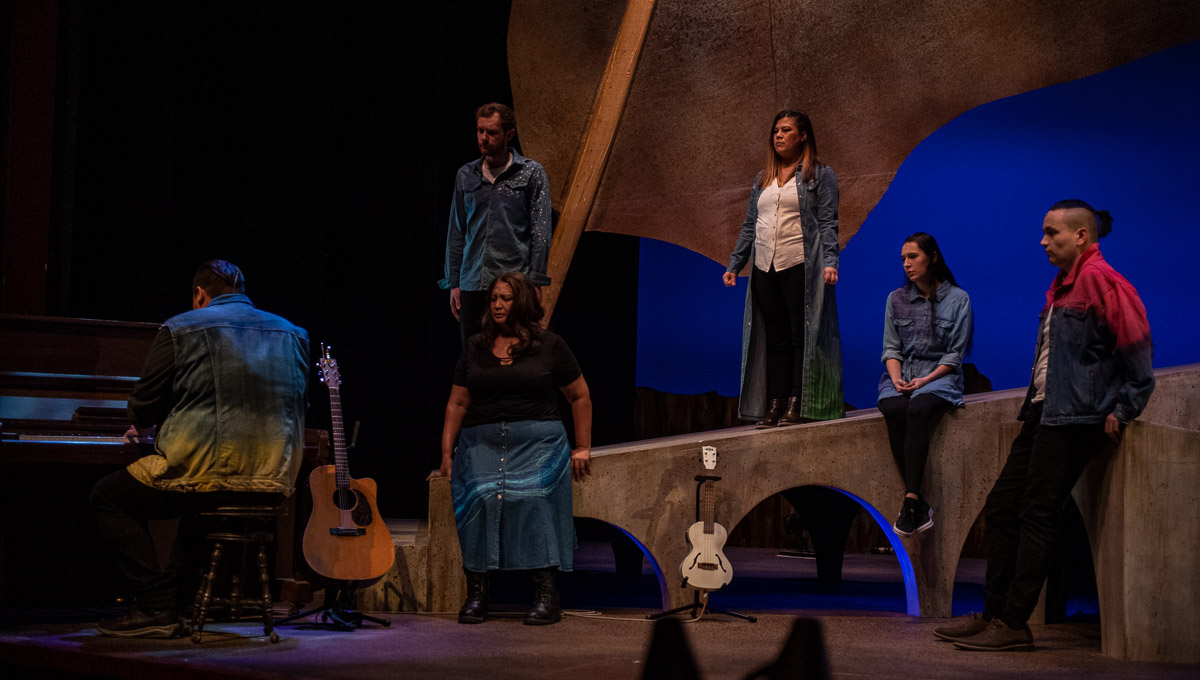 Actors on stage during a performance of Reasonable Doubt, while someone plays piano onstage.